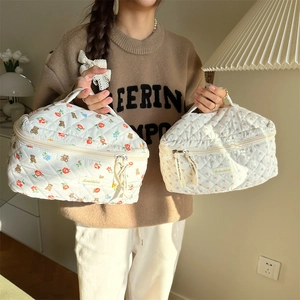 Detailed close-up of quilted cotton cosmetic bag with cute bear print and dual zippers