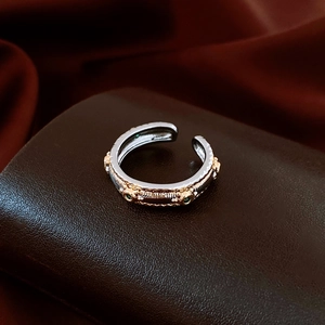 Detail of vintage silver open ring with gold floral patterns and green gemstones