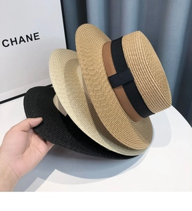 Close-up of three classic straw boater hats in black and beige with elegant black ribbons