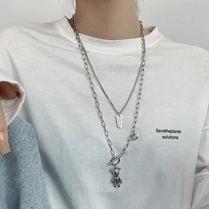 Détail d'un collier argenté à plusieurs rangs avec pendentif ours et fermoir OT