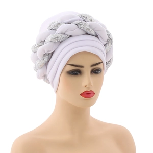 Detail of white turban hat featuring braided silver sequins and a stylish layered design