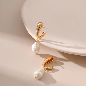 Eleganti orecchini con perle barocche dorate dal design minimalista su sfondo bianco