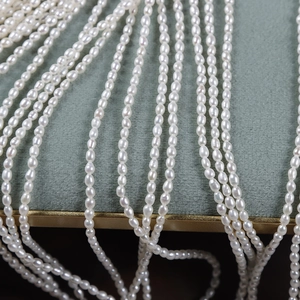 Strands of 2.5mm natural white freshwater rice pearls on green velvet display
