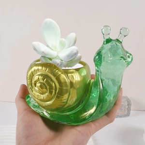 Snail shaped resin planter in green and gold finish holding a succulent plant