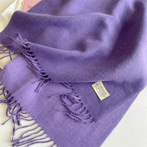 Detailed macro view of soft purple cashmere-feel scarf with fringe and brand woven label
