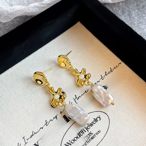 Detailed close-up of Baroque pearl earrings with irregular gold lava texture and tassels