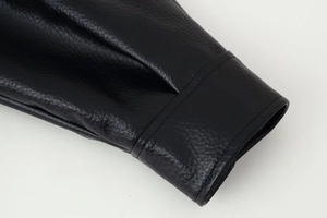 Detailed close-up of stitching and grainy texture on a black faux leather jacket cuff