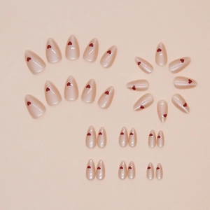 Almond-shaped press-on nails in nude pink with red heart patterns on a plain background