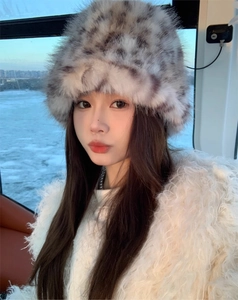 Detail of plush leopard print faux fur bucket hat worn with a soft white winter coat