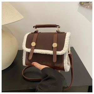Detailed view of retro brown faux leather bag with white fuzzy fleece trim and metal buckles
