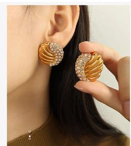 Close-up of gold-plated wing earrings with rhinestones on model's ear showing fine details