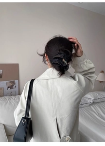 Detail of a black denim scrunchie with contrast stitching worn on a ponytail hairstyle