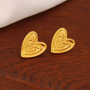 Detail of 18K gold heart stud earrings featuring a multi-layered textured metal design