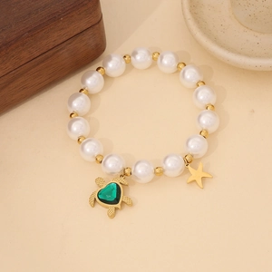 Detailed close-up of a pearl bracelet featuring a gold turtle and star charms on wood