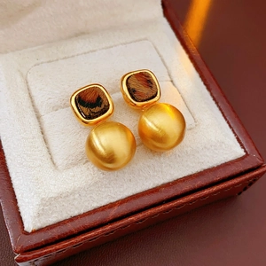 Close-up of vintage French earrings with matte gold beads and brown tortoiseshell pattern