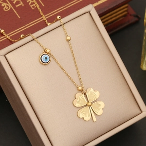 Golden stainless steel necklace with clover and evil eye charms in a jewelry box
