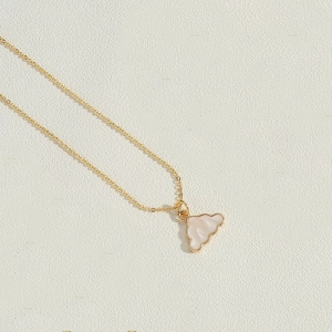 Detailed view of the gold cloud pendant with white inlay on a textured background