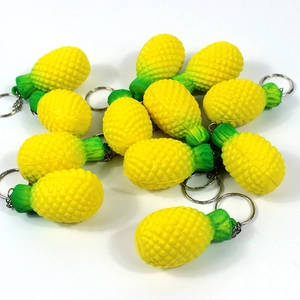 Flat lay macro of multiple yellow pineapple fruit keychains on white background
