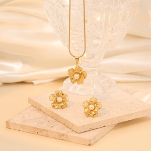 Elegant gold flower jewelry set with white pearls on a necklace and earrings