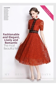 Detailed close-up of intricate red floral lace fabric and black ribbon trim on dress