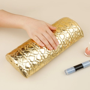 Close-up of golden heart-textured PU leather nail arm rest cushion for manicure support