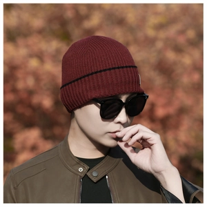 Detail of burgundy ribbed knit beanie showing high-quality wool texture and black stripe
