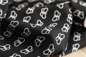 Detail of white butterfly patterns on black silk scarf with elegant fabric texture
