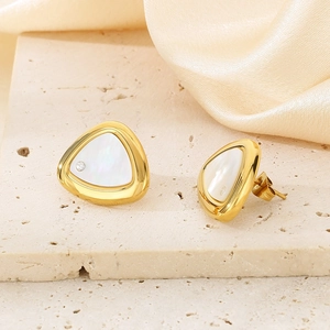 Macro detail of triangle shell earrings with gold frame and diamond accent on silk