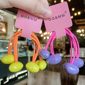 Close-up of candy-colored hair ties with bright oval beads on a brand display card