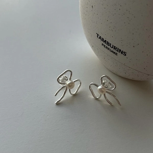 Close-up of 925 sterling silver bow earrings with round white pearl on grey background