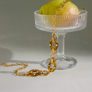 Nahaufnahme der Goldkette mit Bernstein-Resin-Ringen und Kristallverzierung auf Glas