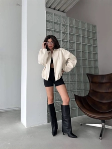 Minimalist beige zipper jacket paired with black shorts and over-the-knee leather boots