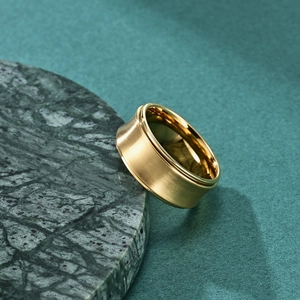 Golden brushed stainless steel spinning ring with a polished inner band on marble stone