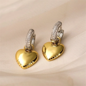 Detail of silver paved ear hoop with a polished golden heart-shaped charm and textured base