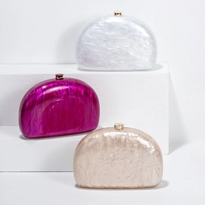 Detail of semi-circular acrylic evening bags with marble texture and gold metal clasps