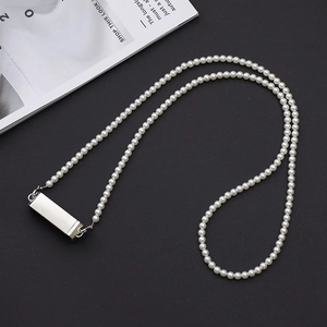 Detailed view of pearl phone strap with a sleek silver metallic pendant on black backdrop