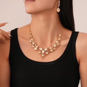 Detail of luxury V-shaped necklace and drop earrings set with champagne crystals on model