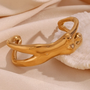 Close-up of a fluid lava-style 18K gold-plated cuff bracelet on satin background