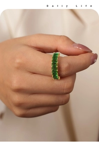 Macro shot of gold plated ring featuring rectangular green zircon stones on model hand