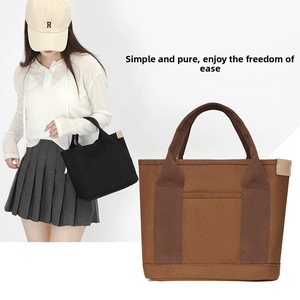 Detail view of canvas tote bags in black and brown with reinforced handles and side accents