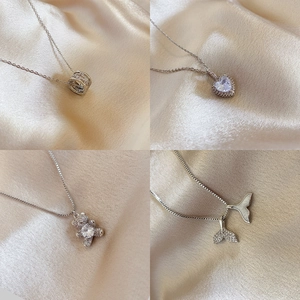 Silver titanium heart and bear pendant necklaces displayed on champagne silk fabric