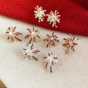 Macro shot of firework-shaped zircon stud earrings with pearls on red festive fabric