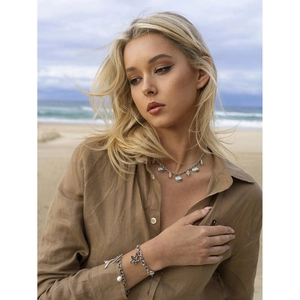 Detailed beach view of starfish and shell charms on 18k gold ocean style jewelry