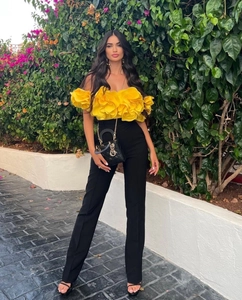 Detailed view of yellow floral bandeau top with 3D petals and black flared pants