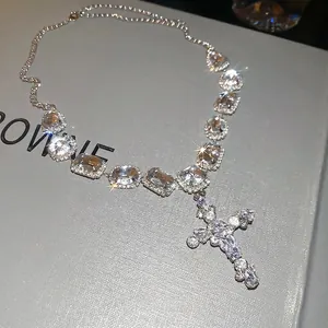 Sparkling silver cross pendant necklace with clear zircon crystals on grey background