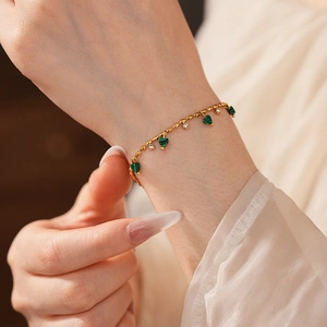 Détail du bracelet chaîne dorée avec pendentifs cœurs verts et zircons blancs étincelants