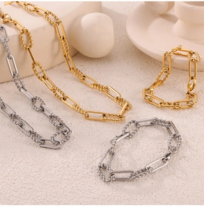 Set of gold and silver twisted chain necklaces and bracelets on a textured surface