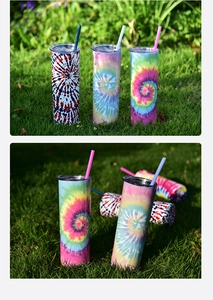 Three tie-dye skinny tumblers with straws displayed on green grass under natural light