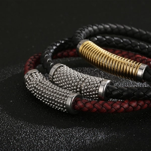 Detailed close-up of braided leather bracelets with gold and silver beads and magnetic clasp