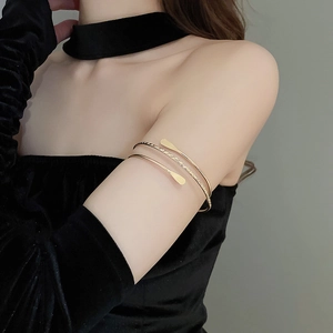 Polished gold multi-layer open arm cuff bracelet worn on model's upper arm